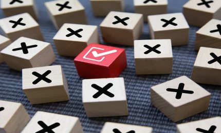 Close-up check mark on cube wooden toy block stack with cross sy