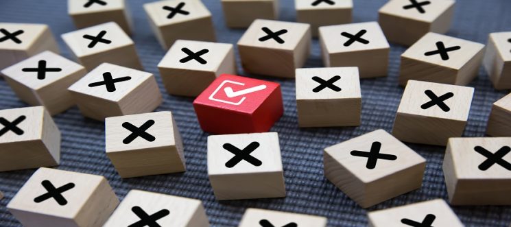 Close-up check mark on cube wooden toy block stack with cross sy